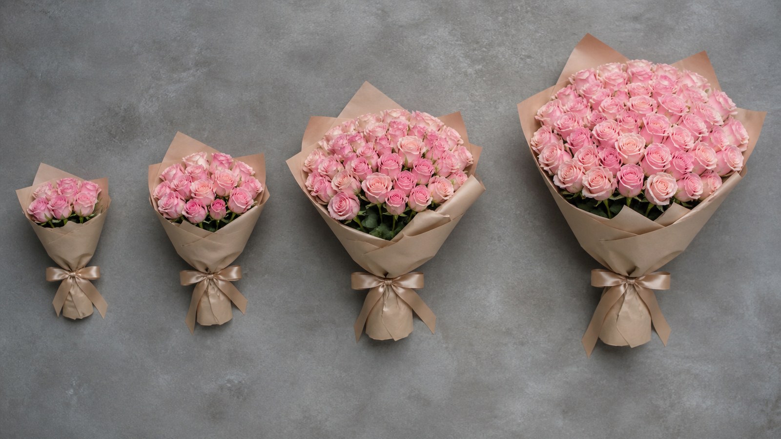 a flat-lay of four bouquets of different sizes on a workshop table — 5, 11, 25 and 51 roses side by side for scale comparison